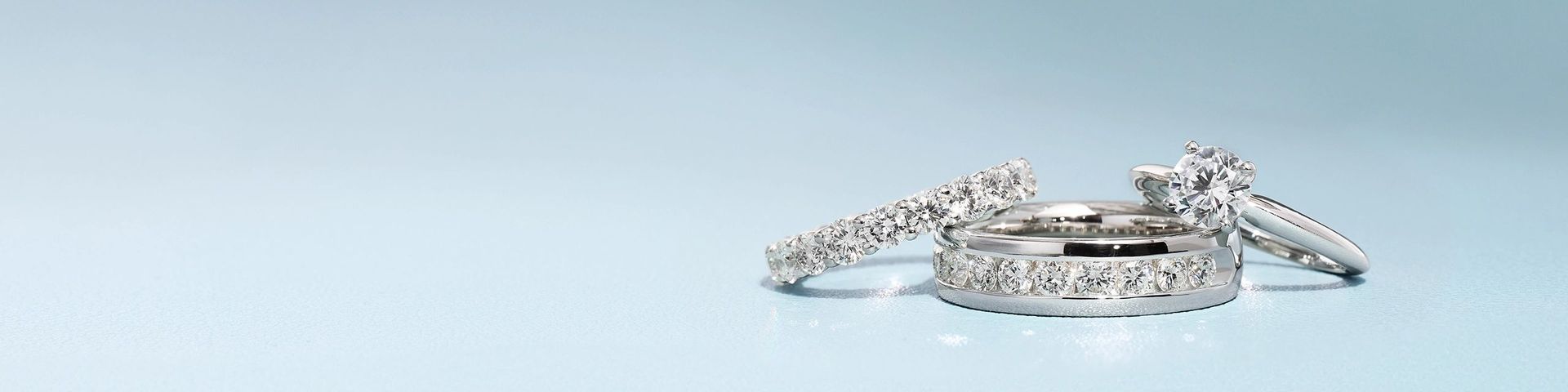 Three diamond rings including two wedding bands and a solitaire engagement ring in white gold. 